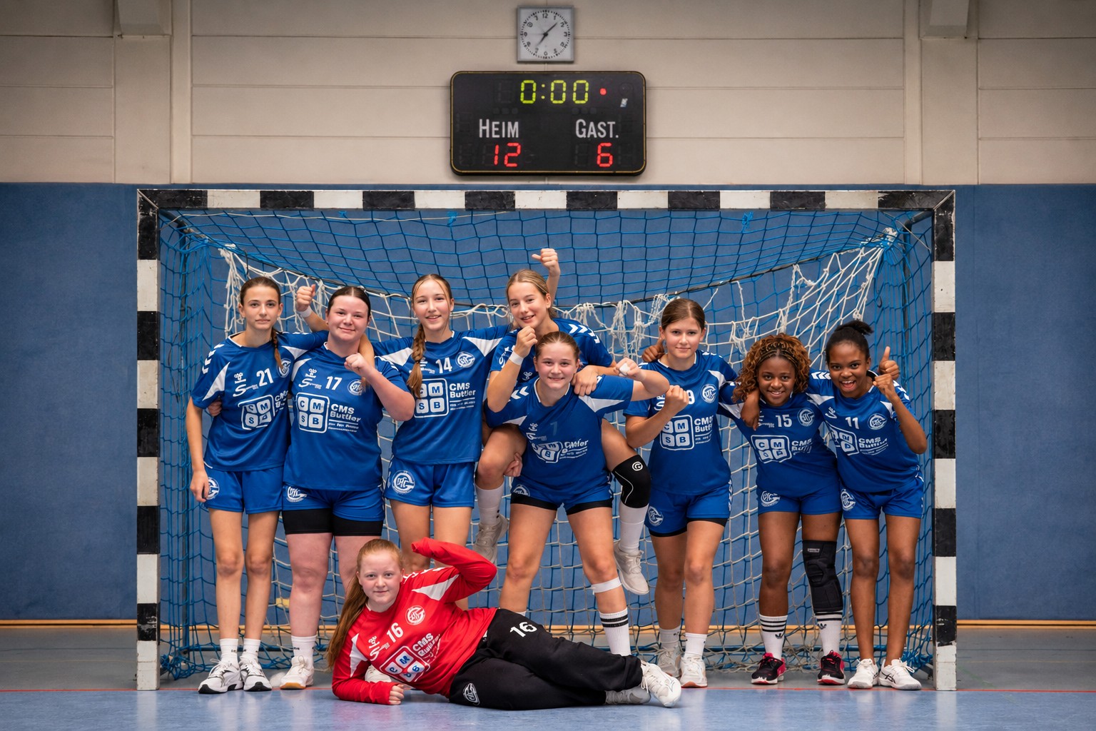 Die weibliche C-Jugend des VfL Gummersbach jubelt gemeinsam vor dem Handballtor in Trikots mit CMS-Buttler-Sponsoring